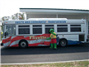 Frog mascot stands next to FACT bus transportation