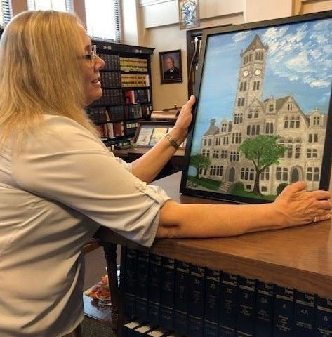 Photograph of Artist of the Month Sue Martin with one of her paintings
