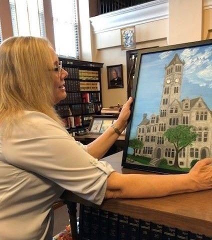 Photograph of Artist of the Month, Sue Martin, with her painting of the Fayette County Courthouse
